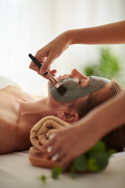 istock Beautician Applying Black Clay Mask 1450999366