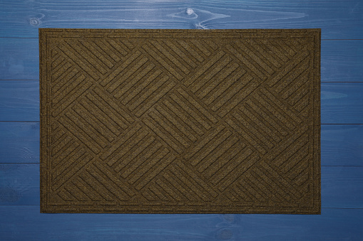 New clean door mat on blue wooden floor, top view