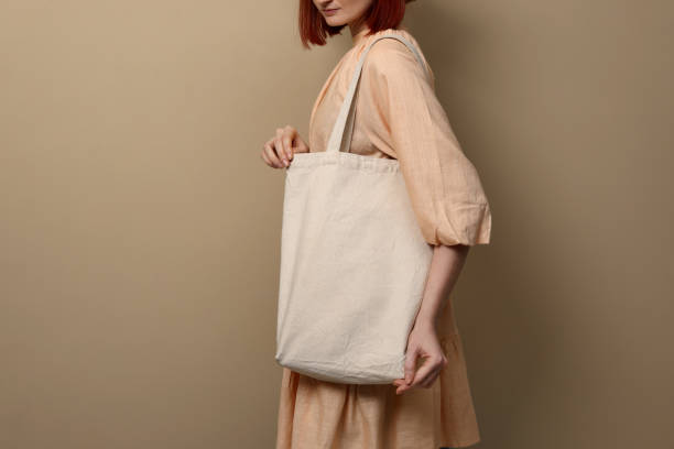 Woman with eco bag on beige background, closeup. Space for text