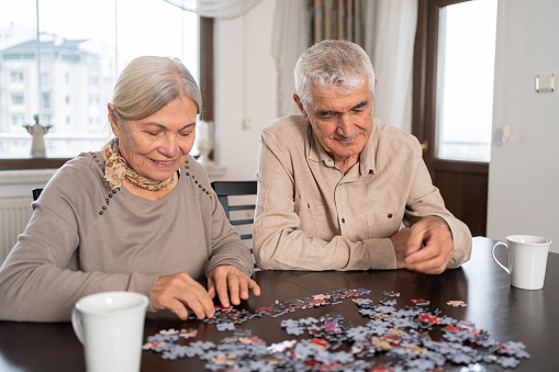 Senior Couple Having Fun With Jigsaw puzzle At Home
