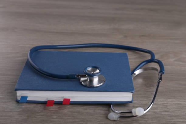 istock Book with sticker marks and stethoscope on wooden table. Medical education 1451001916