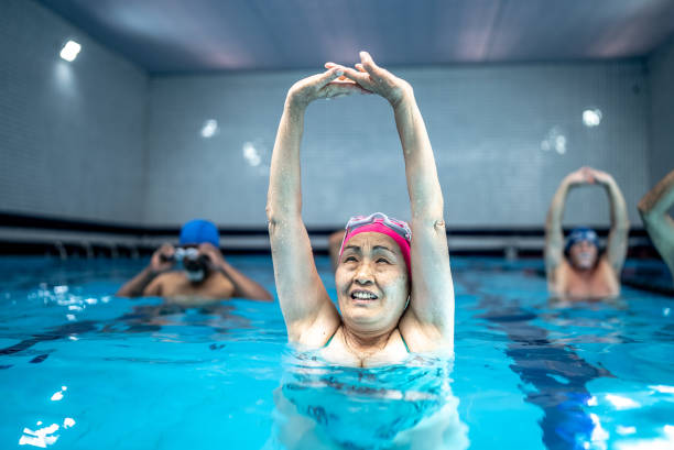 istock Senior woman stretching at swimming pool 1451002097