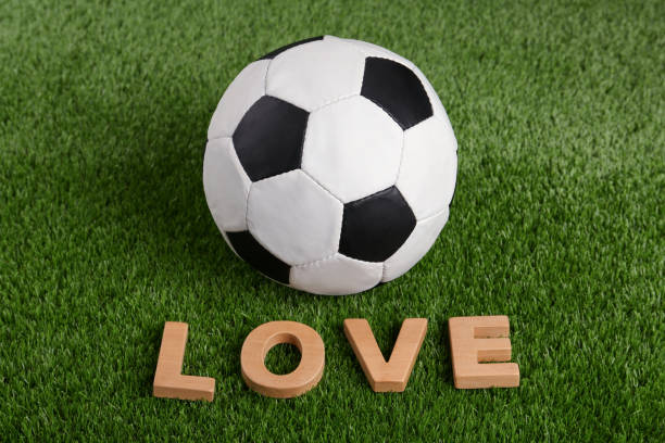 istock Soccer ball and word Love on green grass 1451002109