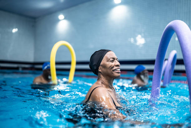 istock Senior woman exercising with noodle float at swimming pool 1451003225