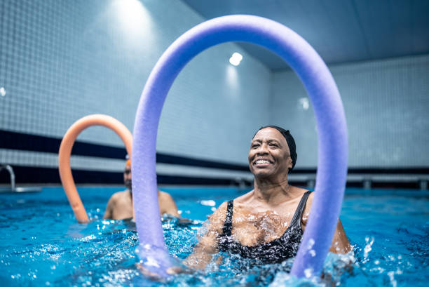 istock Senior woman exercising with noodle float at swimming pool 1451003230
