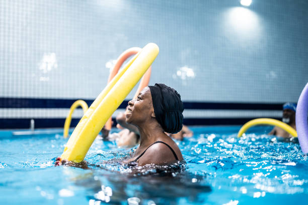 istock Senior woman exercising with noodle float at swimming pool 1451003265