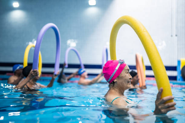 Senior people exercising with noodle float at swimming pool Senior people exercising with noodle float at swimming pool hydrotherapy stock pictures, royalty-free photos & images