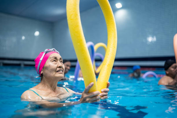 istock Senior woman exercising with noodle float at swimming pool 1451003378