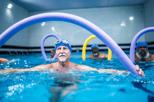 istock Senior man exercising with noodle float at swimming pool 1451003441