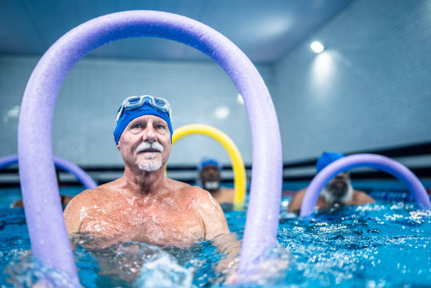 istock Senior man exercising with noodle float at swimming pool 1451003442