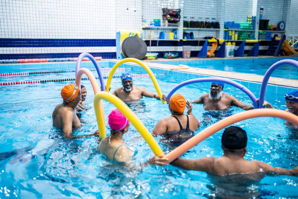 Senior people exercising with noodle float at swimming pool
