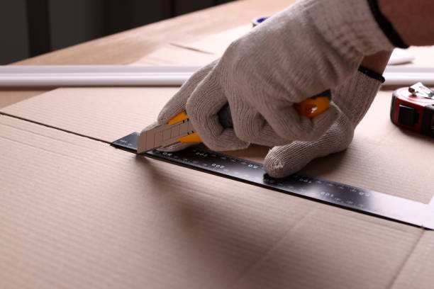 istock Worker cutting cardboard with utility knife and ruler, closeup 1451004441