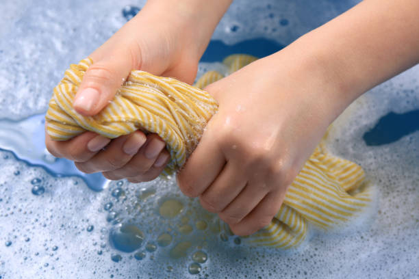 istock Woman wringing garment over basin, closeup. Hand washing laundry 1451005419