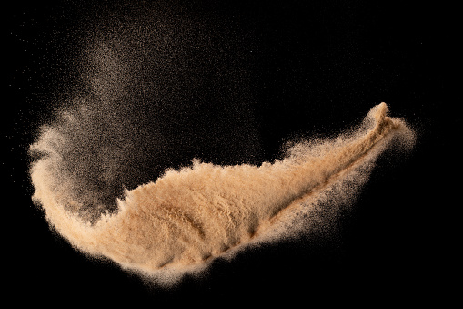 Small size fine Sand flying explosion, Golden grain wave explode. Abstract cloud fly. Yellow colored sand splash silica in Air. Element Black background Isolated high speed throwing freeze shot
