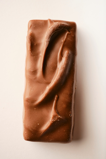 overhead view of an unwrapped budget unhealthy chocolate and caramel bar against a white background.