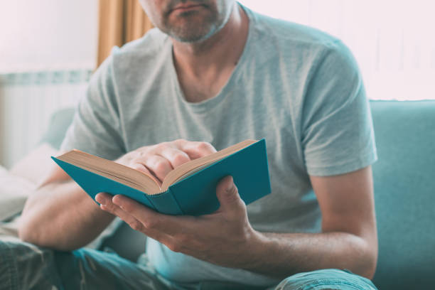istock Man reading book at home, enjoying a good read alone 1451019142