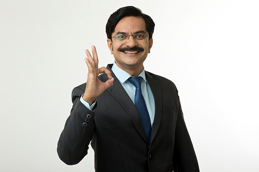 Portrait of confident businessman gesturing perfect on white background