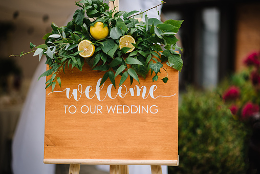 Welcome to our wedding - wedding sign for guests on entrance. Wooden frame or board with welcoming words during marriage ceremony, invitation. Sweet and sour wedding, lemon and greenery decor style.