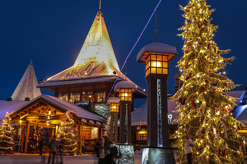 Local people and tourists visit Santa Claus Village (Joulupukki) amusement park, Arctic Circle, Santa's Office, and House of Snowmobiles at night in Rovaniemi in the Lapland region of Finland. It was opened in 1985
