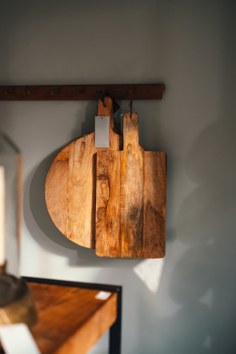 Two wooden cutting boards hanging on a wall in home decor store.