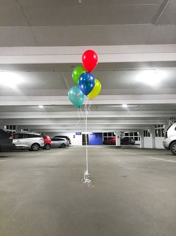 A vertical shot of colorful ballons in a parking garage
