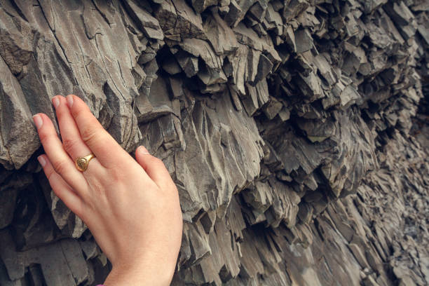 Close up woman touching basalt rock concept photo. Black stone. First view hand photography with textured stone on background. High quality picture for wallpaper, travel blog, magazine, article