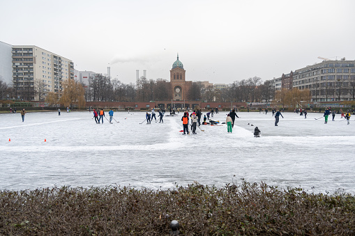 Berlin, Germany - December 17, 2022: People, mainly children, ice-skating on a pond in Engelbecken Park