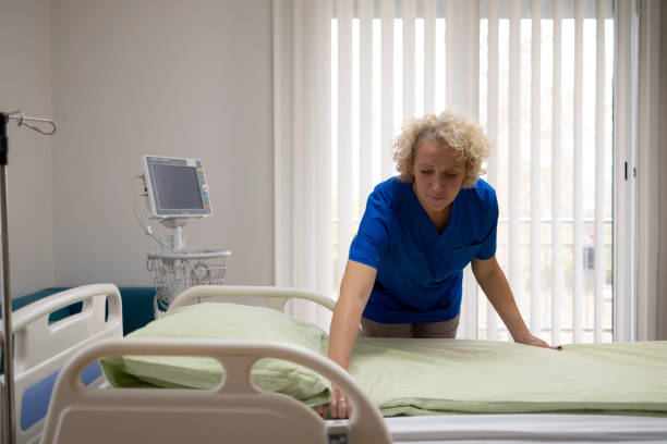 istock Mature female nurse making patient's bed while working in hospital. 1451042460