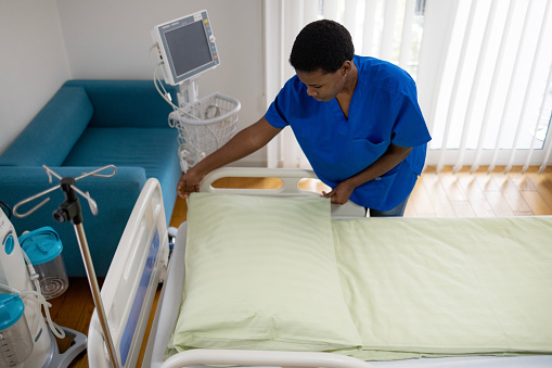 High angle view of young African American nurse preparing a bed while working in hospital.
