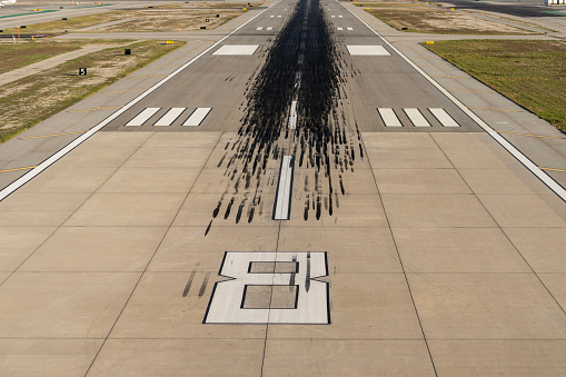 Black skid marks from landing airplanes on airport runway.