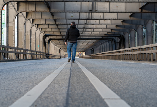 Man walking alone on a empty bridge above the river Elbe in Hamburg, Germany.