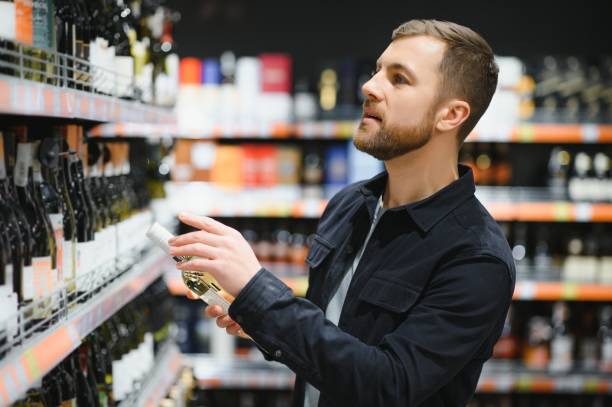 istock Man in a supermarket choosing a wine 1451049186