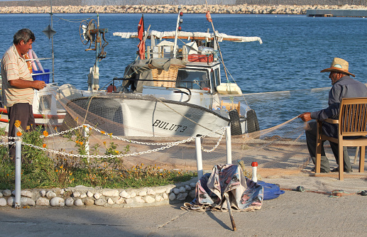 Tasucu, Mersin, Turkey-July 04,2010:Unidentified Fishermen mending their Net by The Sea