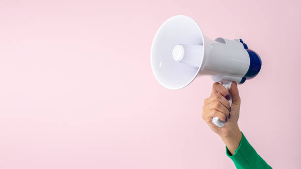 istock Woman hand with megaphone on pink background. Creative announcement concept. 1451064126
