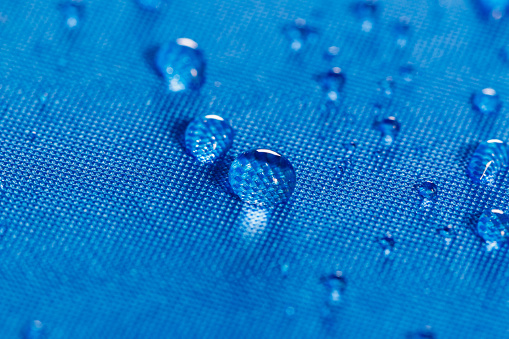 Rain water droplets on  blue waterproof fabric  background