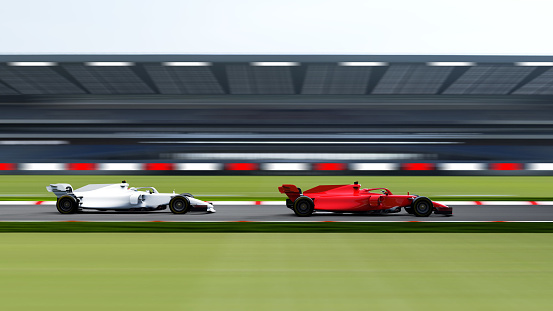 A close up view of two team mates driving at high speed along a straight section of track with an empty  grandstand in the distance. The cars and decals are all custom generic designs. With motion blur to the track.