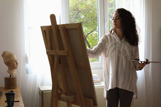 A Caucasian female painting something on an easel