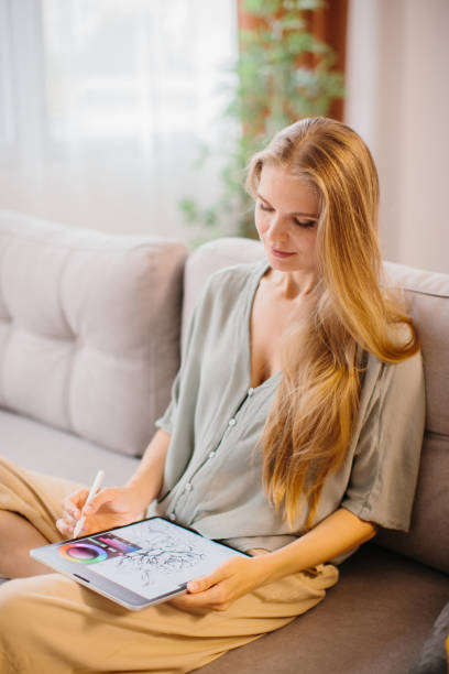 istock Happy young designer drawing on a graphics tablet with a stylus pen. Female graphic designer smiling while working on a new design. Creative young freelancer working in her home office. 1451067810