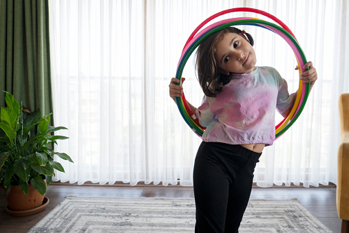cute little girl playing with hula hoop in living room at home.