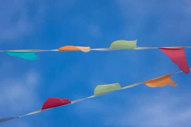 Garland from colorful triangular flags waving on wind against blue sky background. Blurred motion