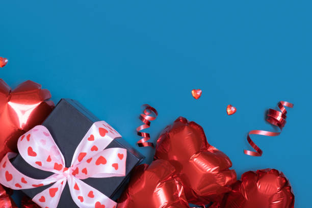 istock Gift box and red heart shape baloons on blue background. Valentines Day greeting card. Copy space 1451070684
