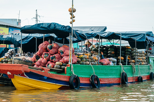 Cai Rang, Can Tho, Vietnam - November 05, 2022: The floating market in the Mekong Delta at Cai Rang in Vietnam. Woman on boat selling pumpkins.