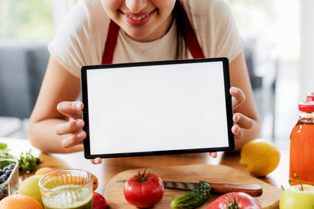 istock Woman hands at kitchen showing tablet with empty blank screen mockup 1451074319