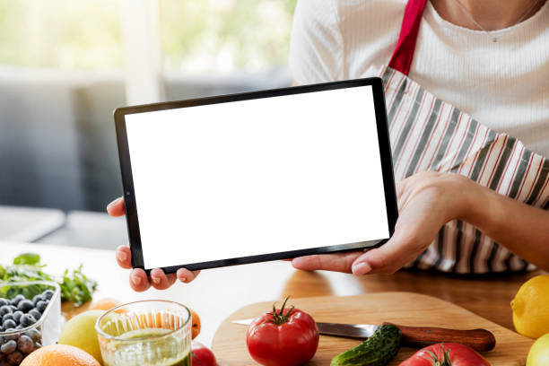 istock Woman hands at kitchen showing tablet with empty blank screen mockup 1451074320