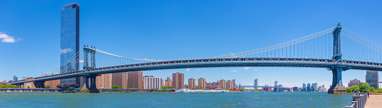 High Resolution Stitched Panoramic Image of Manhattan Bridge, One Manhattan Square High-rise, a 72-story skyscraper at the foot of the Bridge, Residential Buildings of Manhattan Lower East Side, Williamsburg Bridge and Water of East River. Blue Morning Sky is in background, New York City, USA. Canon EOS 6D (full frame sensor) DSLR and Canon EF 24-105mm F/4L IS lens. 3.5:1 Image Aspect Ratio. This image is downsized to 50MP. Original image resolution was 64MP or 15041 x 4254 px.