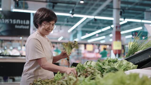 Asian woman choosing vegetable at minimart.