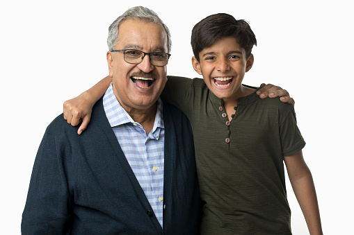 Cheerful boy and grandfather arms around on white background
