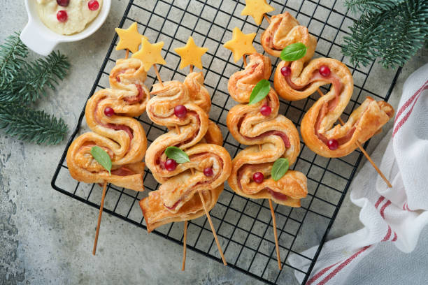 istock Christmas or New Year appetizer. Christmas tree shape puff pastry buns with cheese and ham. Group of Christmas tree shapes on stand for hot. Festive idea for Christmas or New Year dinner. Top view. 1451085373