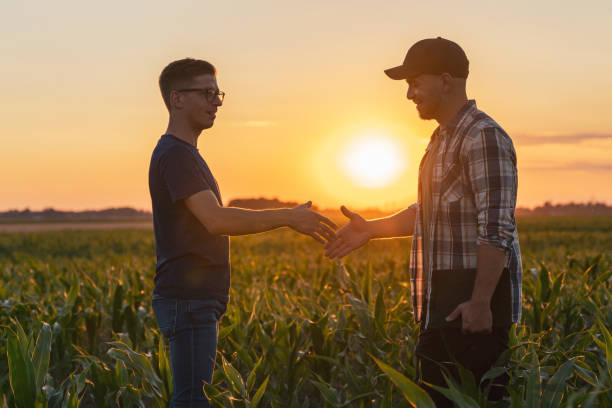 istock Male farmer and agronomist shaking hands in corn field 1451085859