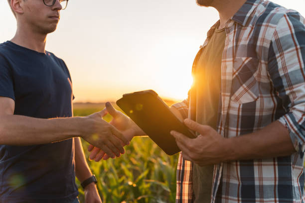 istock Male farmer and agronomist shaking hands in corn field 1451085873